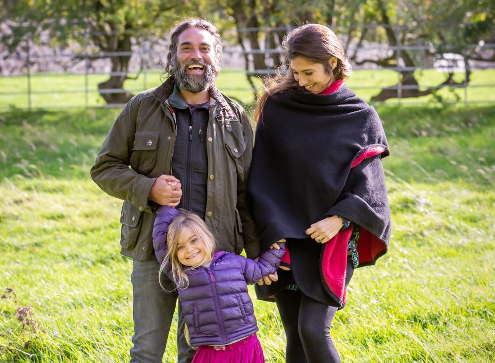 Family photograph of Jarvis, Katie and their child walking in a green land