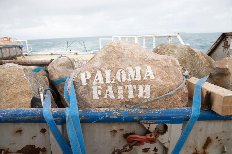 Donor names are painted in chalk ahead of the boulder placement