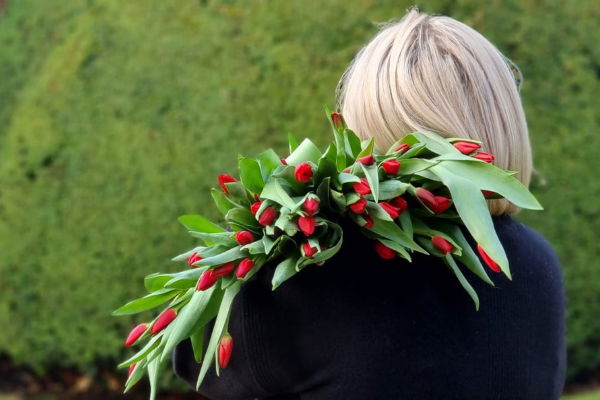 Jane Bradley, founder of Brook & Earl, with her back turned and a huge bouquet of red tulips cascading over her shoulder