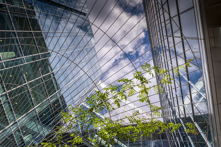 Low-angle view of the Lloyds of London building, with a tree and blue sky