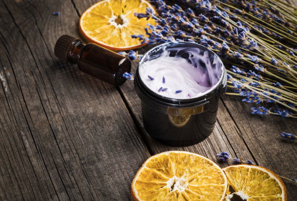 Organic moisturising cream with dried lavender and orange on a wooden table