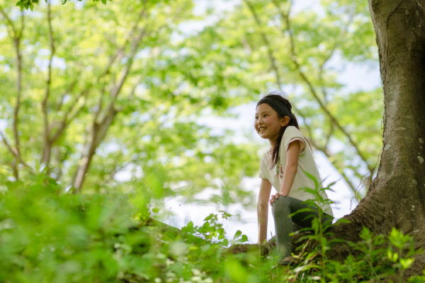 Girl smiling as she sits in the shade of a tree
