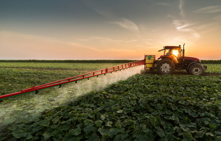 Tractor spraying pesticides on vegetable field with sprayer at spring