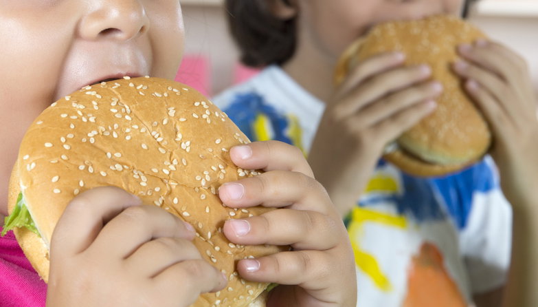 Young boy and girl eating hamburgers