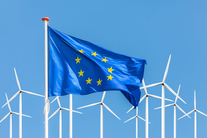 Official flag of the European Union in front of a large windpark with wind turbines