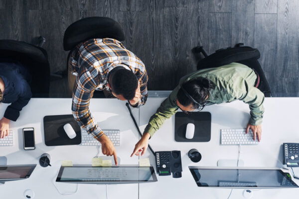 High-angle shot of two people working in an office, comparing information on computers