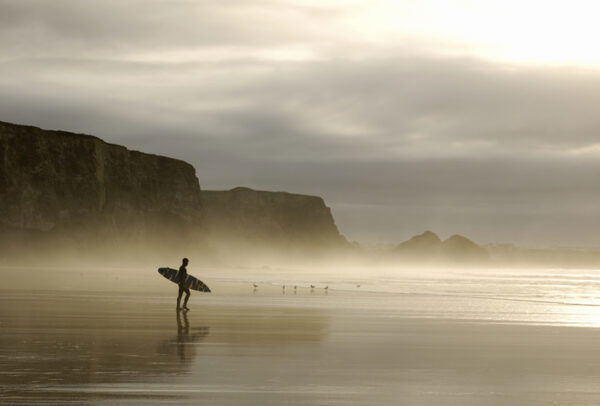 Winter surfer walking through mist in Cornwall