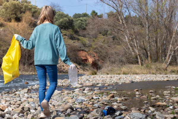 Woman walking the riverbank looking for rubbish