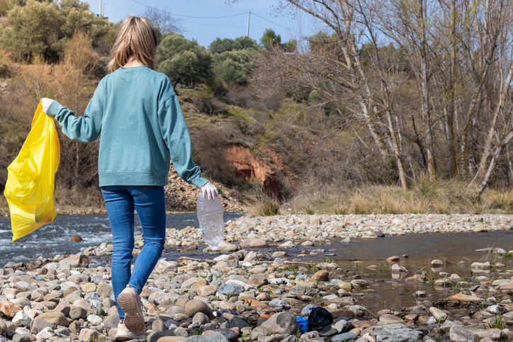 Woman walking the riverbank looking for rubbish