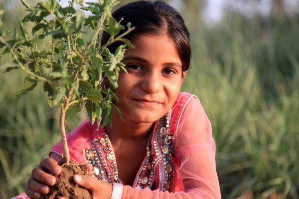 Elementary-age girl outside in nature, holding plant in hands