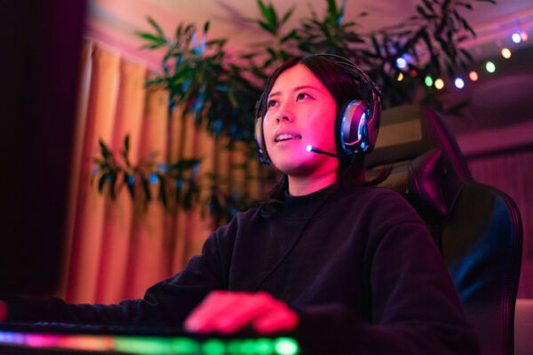 A young woman smiling, her face lit up by the screen she is looking at