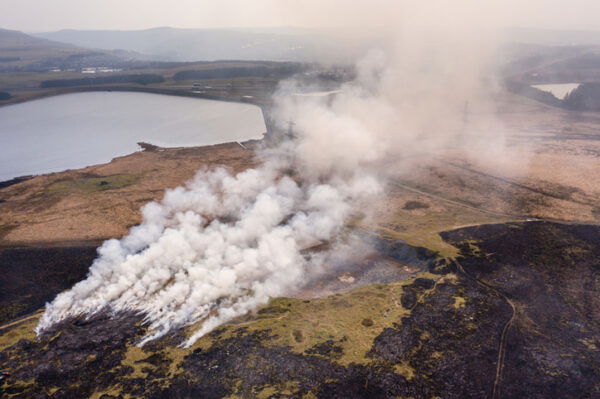 Aerial view of a huge wildfire on high level moorland next to a reservoir (Llangynidr Moors, Wales)