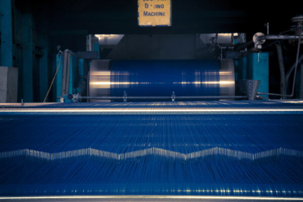 Blue Dyed thread getting wrapped on spools for weaving looms after getting dyed on rope dyeing machine