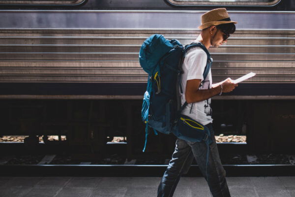 Traveller with rucksack walking along platform at train station