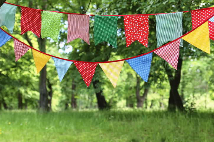 Close-up of bunting flags hanging among trees in a summer garden
