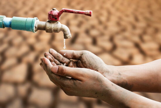 Hand of people wating for a drip of water from a faucet at desert