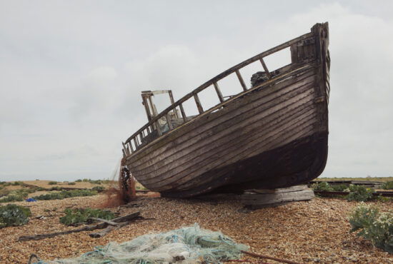 Abandoned ship on pebble beach, with discarded fishing nets