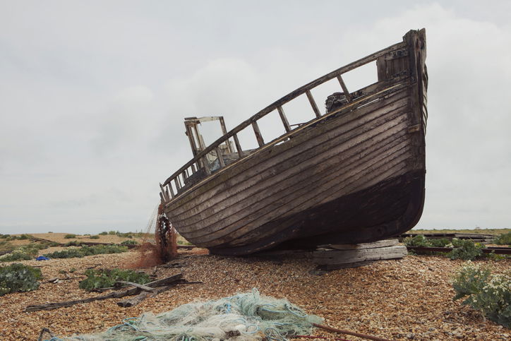 Abandoned ship on pebble beach, with discarded fishing nets
