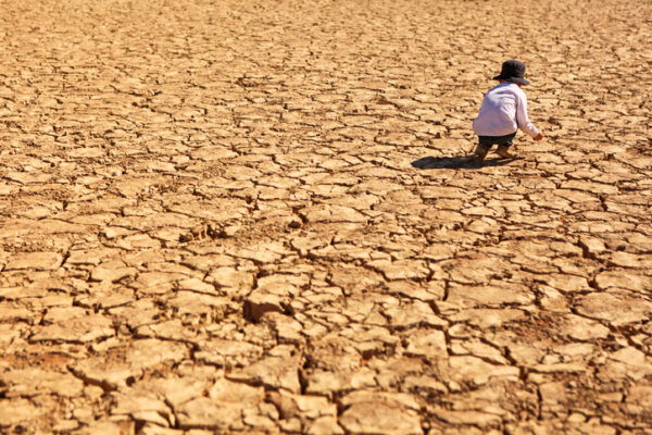 Child is playing on dry brown cracked land in the heat of the desert at Deadvlei in Namib-Naukluft National Park in Namibia, Africa