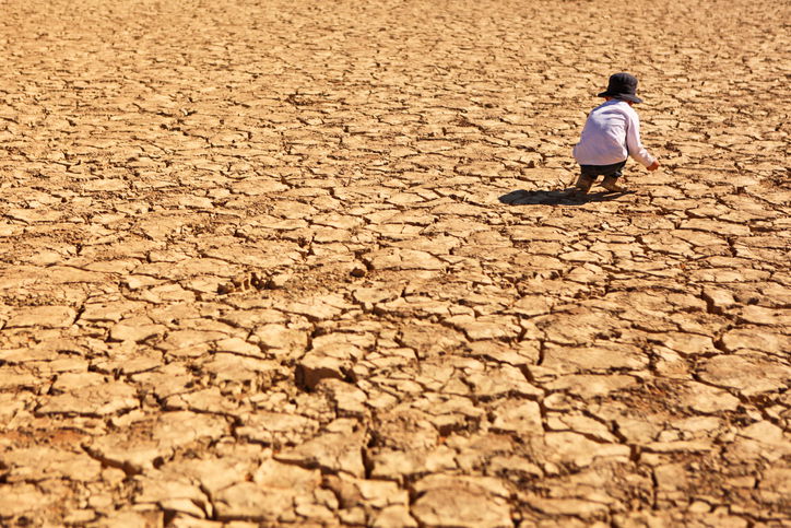 Child is playing on dry brown cracked land in the heat of the desert at Deadvlei in Namib-Naukluft National Park in Namibia, Africa